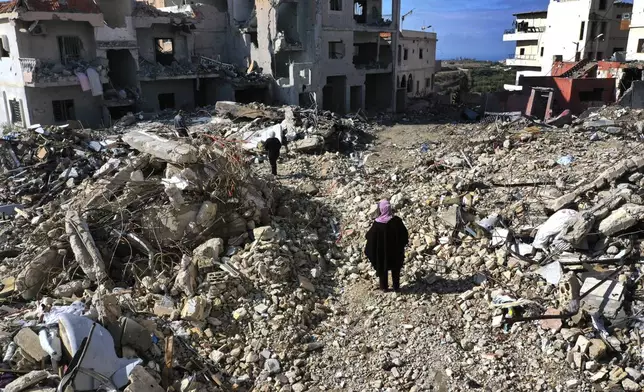 Residents walk past destroyed buildings as they return to Qana village, southern Lebanon, Thursday, Nov. 28, 2024 following a ceasefire between Israel and Hezbollah that went into effect on Wednesday.(AP Photo/Hussein Malla)