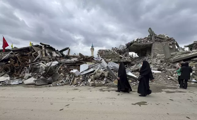 Residents walk past destroyed buildings as they return to Nabatiyeh, southern Lebanon, Thursday, Nov. 28, 2024 following a ceasefire between Israel and Hezbollah that went into effect on Wednesday. (AP Photo/Bassam Hatoum)