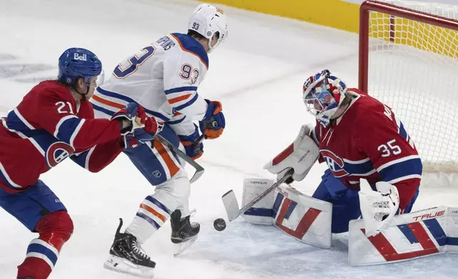 Montreal Canadiens' goaltender Sam Montembeault (35) makes a save against Edmonton Oilers' Ryan Nugent-Hopkins (93) as Canadiens' Kaiden Guhle (21) defends during the first period of an NHL hockey game in Montreal, Monday, Nov. 18, 2024. (Christinne Muschi/The Canadian Press via AP)