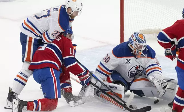 Edmonton Oilers goaltender Calvin Pickard (30) stops a shot by Montreal Canadiens' Brendan Gallagher (11) as Oilers' Brett Kulak (27) defends during second-period NHL hockey game action in Montreal, Monday, Nov. 18, 2024. (Christinne Muschi/The Canadian Press via AP)