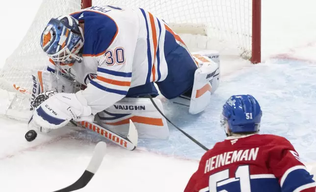 Edmonton Oilers' goaltender Calvin Pickard (30) covers up the puck as Montreal Canadiens' Emil Heineman (51) drives in for the rebound during the first period of an NHL hockey game in Montreal, Monday, Nov. 18, 2024. (Christinne Muschi/The Canadian Press via AP)