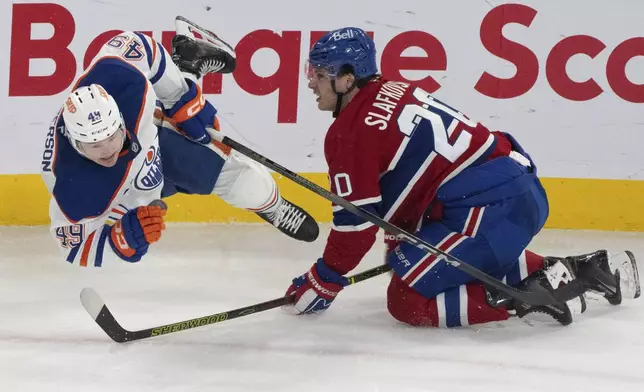 Edmonton Oilers' Ty Emberson (49) is upended by Montreal Canadiens' Juraj Slafkovsky (20) during second-period NHL hockey game action in Montreal, Monday, Nov. 18, 2024. (Christinne Muschi/The Canadian Press via AP)