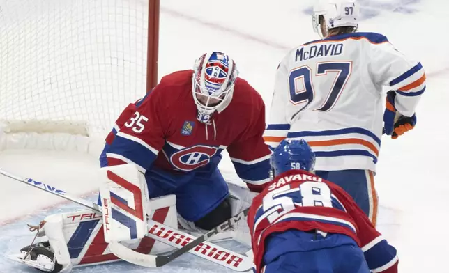 Montreal Canadiens goaltender Sam Montembeault (35) stops a shot by Edmonton Oilers' Connor McDavid (97) as Canadiens' David Savard (58) defends during second-period NHL hockey game action in Montreal, Monday, Nov. 18, 2024. (Christinne Muschi/The Canadian Press via AP)