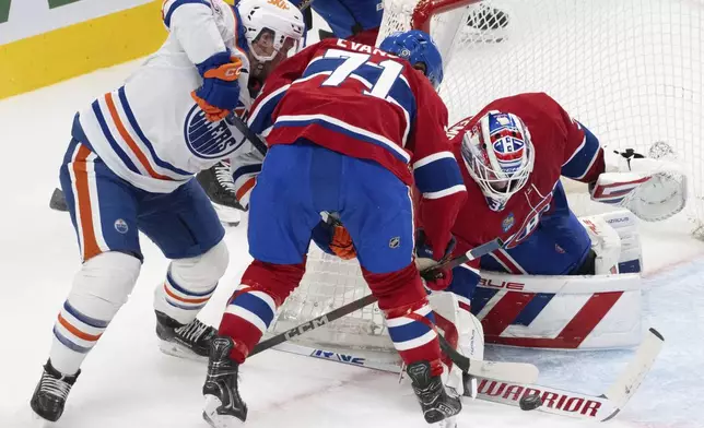 Montreal Canadiens goaltender Sam Montembeault, right, stops a shot as Edmonton Oilers' Jeff Skinner, left, and Canadiens' Jake Evans (71) look for the rebound during second-period NHL hockey game action in Montreal, Monday, Nov. 18, 2024. (Christinne Muschi/The Canadian Press via AP)