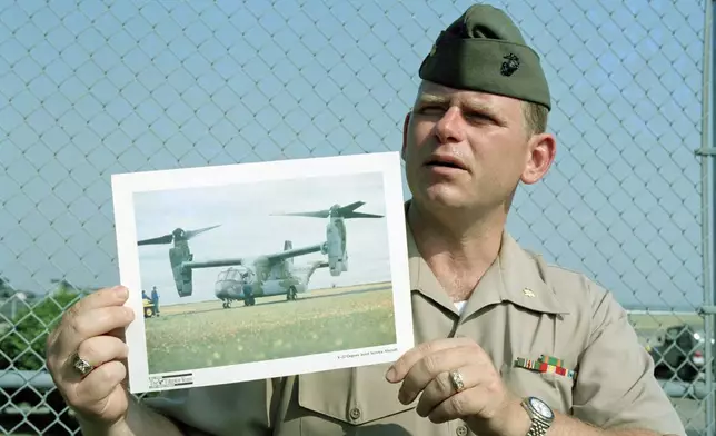 FILE - Maj. Barry Moore shows a photo of a V-22 Osprey aircraft at a news conference, July 20, 1992, at Quantico Marine Air Station in Quantico, Va., after an experimental V-22 tilt-rotor aircraft crashed into the Potomac River near the air station. (AP Photo/Charles Tasnadi, File)