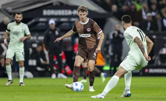 St. Pauli's David Nemeth, centre, and Moenchengladbach's Tim Kleindienst fight for the ball during the German Bundesliga soccer match between Borussia Moenchengladbach and FC St. Pauli at the Borussia Park in Moenchengladbach, Germany, Sunday, Nov. 24, 2024. (David Inderlied/dpa via AP)