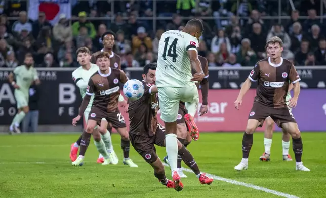 Moenchengladbach's Alassane Plea, centre, scores the opening goal during the German Bundesliga soccer match between Borussia Moenchengladbach and FC St. Pauli at the Borussia Park in Moenchengladbach, Germany, Sunday, Nov. 24, 2024. (David Inderlied/dpa via AP)