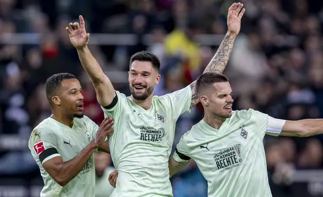 Moenchengladbach's Tim Kleindienst, centre, celebrates with Julian Weigl, right, and Alassane Plea after scoring his side's second goal during the German Bundesliga soccer match between Borussia Moenchengladbach and FC St. Pauli at the Borussia Park in Moenchengladbach, Germany, Sunday, Nov. 24, 2024. (David Inderlied/dpa via AP)