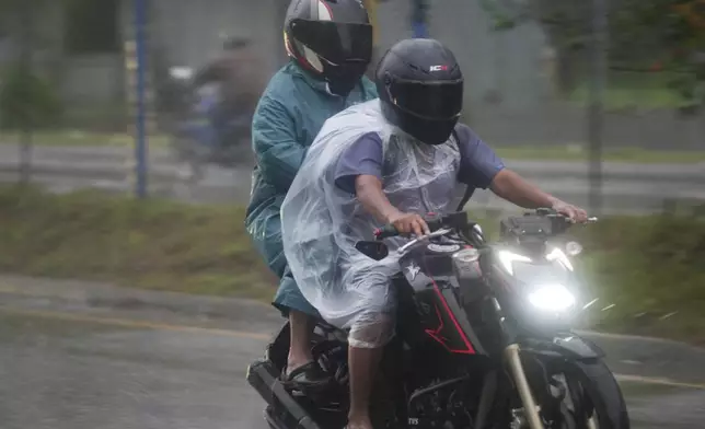 Motorcyclists cover themselves with plastic sheets during rains brought on by tropical storm Sara in San Pedro Sula, Honduras, Friday, Nov. 15, 2024. (AP Photo/Moises Castillo)