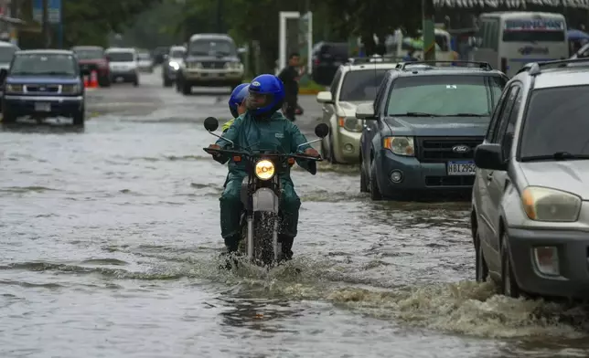 A motorcyclist rides on a street flooded by rains brought on by Tropical Storm Sara in La Lima, Honduras, Friday, Nov. 15, 2024. (AP Photo/Moises Castillo)
