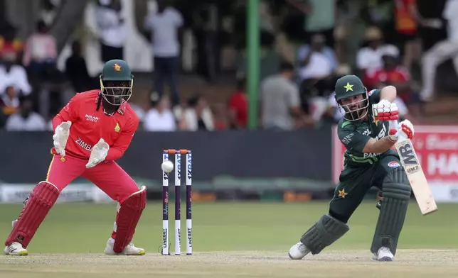 Pakistan's, Kamran Ghulan, right, plays a stroke, in front of Zimbabwe's wicketkeeper Tadiwanashe Marumani, left, on the first day of the ODI cricket match between Zimbabwe and Pakistan at Queens Sports Club in Bulawayo, Zimbabwe, Sunday Nov. 24, 2024 (AP Photo/Wonder Mashura)