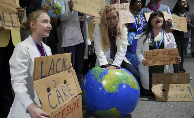 Activist Ann Carlotta Oltmanns, center, pretends to resuscitate Earth with others during a demonstration at the COP29 U.N. Climate Summit, Monday, Nov. 18, 2024, in Baku, Azerbaijan. (AP Photo/Peter Dejong)