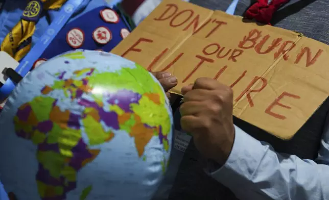 A demonstrators holds a sign that reads "don't burn our future" at the COP29 U.N. Climate Summit, Monday, Nov. 18, 2024, in Baku, Azerbaijan. (AP Photo/Peter Dejong)