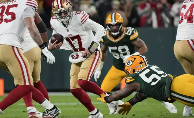 San Francisco 49ers quarterback Brandon Allen (17) avoids the tackle against Green Bay Packers defensive end Kingsley Enagbare (55) during the first half of an NFL football game on Sunday, Nov. 24, 2024 in Green Bay, Wis. (AP Photo/Morry Gash)