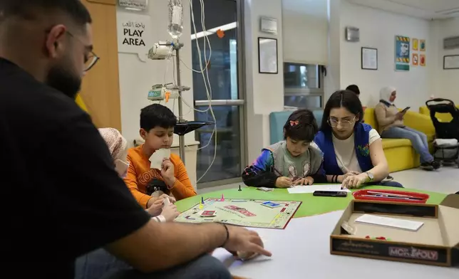 Carol Zeghayer, 9, second right, a girl who suffers from leukaemia, attends with a volunteer who offers her a compassionate care and entertainment session ahead of her treatment at the Children's Cancer Center of Lebanon, in Beirut, Lebanon, Friday, Nov. 15, 2024. (AP Photo/Hussein Malla)