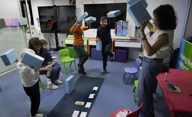 Children who suffers from cancer, enjoy at a playroom with a volunteer ahead of their treatments at the Children's Cancer Center of Lebanon, in Beirut, Lebanon, Friday, Nov. 15, 2024. (AP Photo/Hussein Malla)