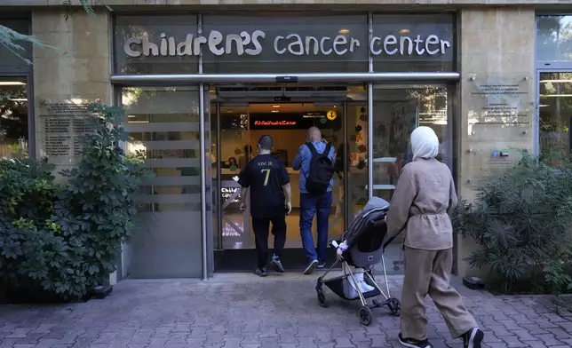 Patents with their child enter the Children's Cancer Center of Lebanon to receive their treatments, in Beirut, Lebanon, Friday, Nov. 15, 2024. (AP Photo/Hussein Malla)