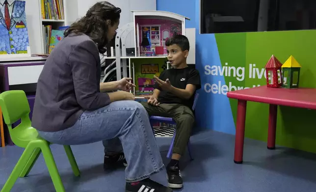 Mohammad Mousawi, 8, a displaced boy from the southern suburb of Beirut who suffers from leukaemia, attends with a volunteer who offers him a compassionate care and entertainment ahead of his weekly treatment at the Children's Cancer Center of Lebanon, in Beirut, Lebanon, Friday, Nov. 15, 2024. (AP Photo/Hussein Malla)