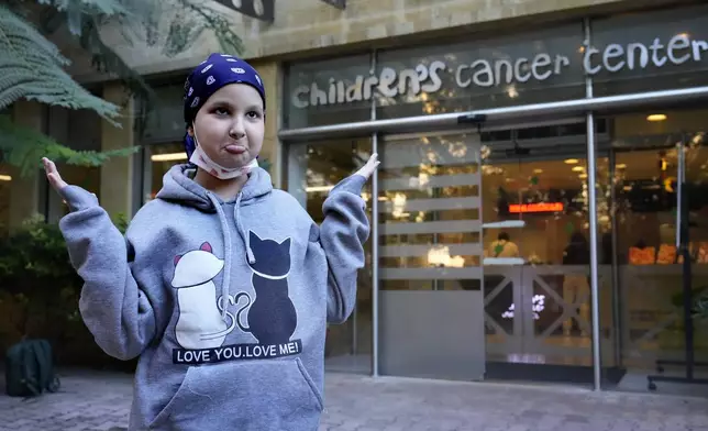 Asinat al Lahham, 9, a Syrian-Palestinian girl who escaped the war in Syria with her family and who suffers from leukaemia, gestures outside the Children's Cancer Center of Lebanon, in Beirut, Lebanon, Friday, Nov. 15, 2024. (AP Photo/Hussein Malla)