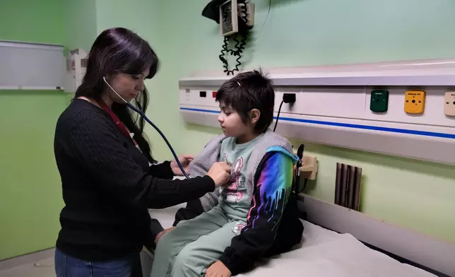 Doctor Dolly Noun, a pediatric hematologist and oncologist, checks Carol Zeghayer, 9, a girl who suffers from leukaemia ahead of her treatment at the Children's Cancer Center of Lebanon, in Beirut, Lebanon, Friday, Nov. 15, 2024. (AP Photo/Hussein Malla)