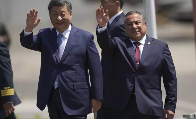 Chinese President Xi Jinping, left, and Peru's Prime Minister Gustavo Adrianzen, wave on the airport tarmac after Xi's arrival to attend the Asia-Pacific Economic Cooperation (APEC) summit, in Lima, Peru, Thursday, Nov. 14, 2024. (AP Photo/Guadalupe Pardo)