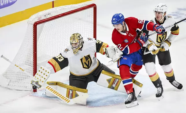 Vegas Golden Knights goaltender Adin Hill (33) makes a save as Montreal Canadiens' Lucas Condotta (82) and Knights' Zach Whitecloud (2) move in during the first period of an NHL hockey game in Montreal, Saturday, Nov. 23, 2024. (Graham Hughes/The Canadian Press via AP)