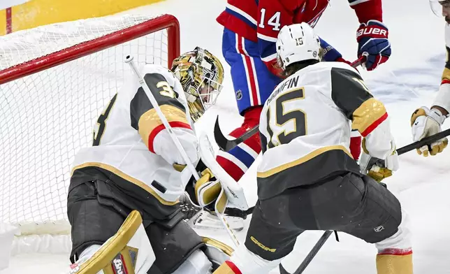 Vegas Golden Knights goaltender Adin Hill (33) stops Montreal Canadiens' Nick Suzuki (14) as Knights' Noah Hanifin (15) defends during first period NHL hockey action in Montreal, Saturday, Nov. 23, 2024. (Graham Hughes/The Canadian Press via AP)