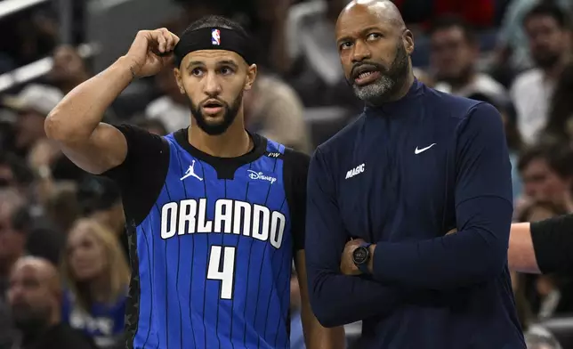 Orlando Magic head coach Jamahl Mosley, right, gives instructions to guard Jalen Suggs (4) during the first half of an Emirates NBA Cup basketball game against the Philadelphia 76ers, Friday, Nov. 15, 2024, in Orlando, Fla. (AP Photo/Phelan M. Ebenhack)