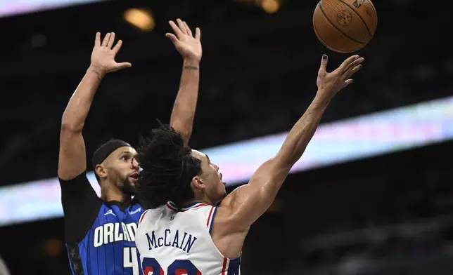 Philadelphia 76ers guard Jared McCain (20) puts up a shot as Orlando Magic guard Jalen Suggs (4) defends during the second half of an Emirates NBA Cup basketball game, Friday, Nov. 15, 2024, in Orlando, Fla. (AP Photo/Phelan M. Ebenhack)