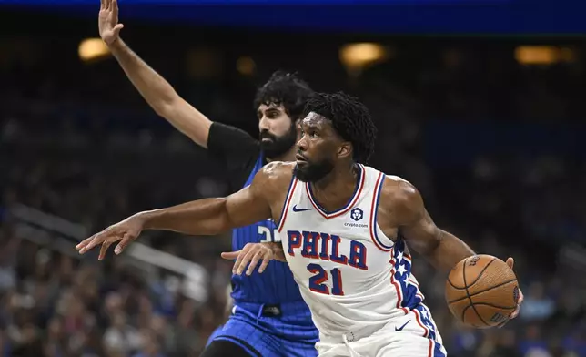 Philadelphia 76ers center Joel Embiid (21) drives past Orlando Magic center Goga Bitadze, rear, during the first half of an Emirates NBA Cup basketball game, Friday, Nov. 15, 2024, in Orlando, Fla. (AP Photo/Phelan M. Ebenhack)