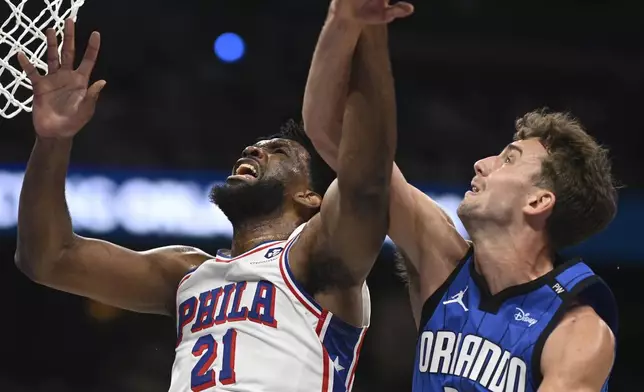 Philadelphia 76ers center Joel Embiid (21) is fouled by Orlando Magic forward Franz Wagner (22) while going up to shoot during the first half of an Emirates NBA Cup basketball game, Friday, Nov. 15, 2024, in Orlando, Fla. (AP Photo/Phelan M. Ebenhack)