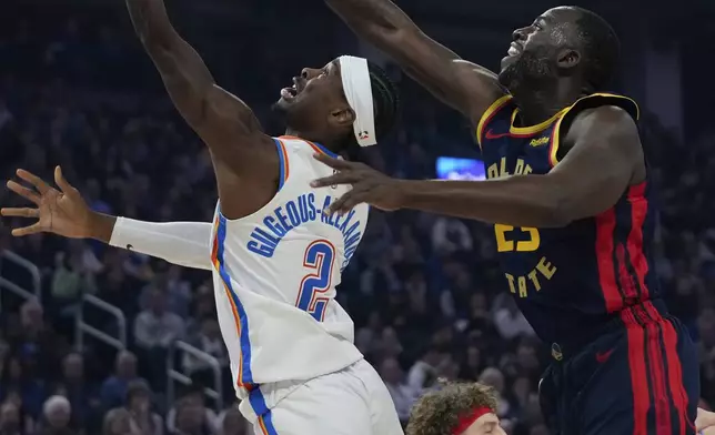 Oklahoma City Thunder guard Shai Gilgeous-Alexander (2) shoots while defended by Golden State Warriors forward Draymond Green during the first half of an NBA basketball game Wednesday, Nov. 27, 2024, in San Francisco. (AP Photo/Godofredo A. Vásquez)