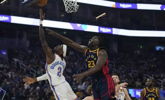 Oklahoma City Thunder guard Shai Gilgeous-Alexander (2) shoots while defended by Golden State Warriors forward Draymond Green during the first half of an NBA basketball game Wednesday, Nov. 27, 2024, in San Francisco. (AP Photo/Godofredo A. Vásquez)