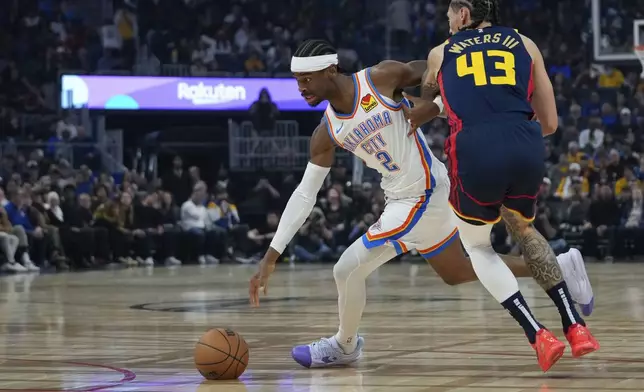 Oklahoma City Thunder guard Shai Gilgeous-Alexander, left, moves the ball past Golden State Warriors forward Lindy Waters III during the first half of an NBA basketball game Wednesday, Nov. 27, 2024, in San Francisco. (AP Photo/Godofredo A. Vásquez)