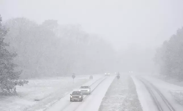 Cars drive along a snow-covered road in the forest of Fontainebleau, south of Paris, Thursday, Nov. 21, 2024. (AP Photo/Thibault Camus)