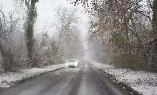 A car drives along a road in the forest of Fontainebleau during a snowfall, near Fontainebleau, south of Paris, Thursday, Nov. 21, 2024. (AP Photo/Thibault Camus)