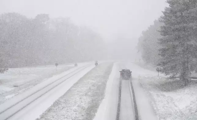 A car drives along a snow-covered road in the forest of Fontainebleau, south of Paris, Thursday, Nov. 21, 2024. (AP Photo/Thibault Camus)