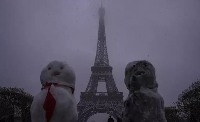 Snow figures are seen near to the Eiffel Tower as snow falls in Paris, Thursday, Nov. 21, 2024. (AP Photo/Louise Delmotte)