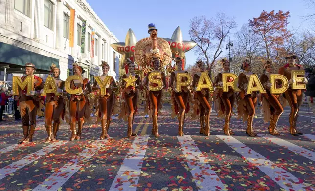 FILE - Parade performers lead the Tom Turkey float down Central Park West at the start of the Macy's Thanksgiving Day parade on Nov. 23, 2023, in New York. (AP Photo/Jeenah Moon, File)