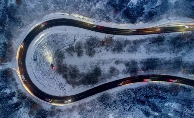 Cars drive through curve in a forest of the Taunus region near Frankfurt, Germany, after snow falls during the night on Thursday, Nov. 21, 2024. (AP Photo/Michael Probst)