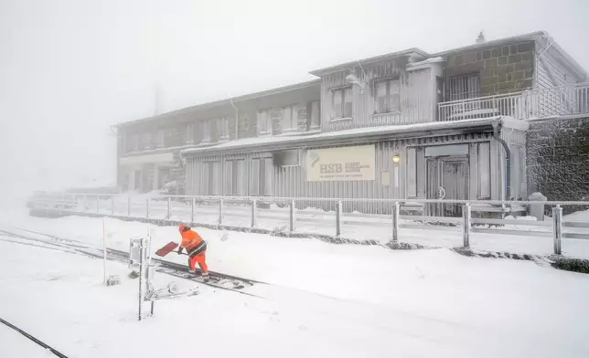 A railroad worker clears the tracks of snow on northern Germany's 1,142-meter (3,743 feet) highest mountain 'Brocken' at the Harz mountains near Schierke, Germany, Wednesday, Nov. 20, 2024. (AP Photo/Matthias Schrader)