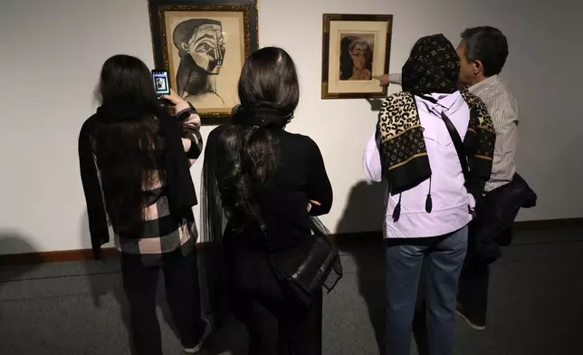 Visitors look at artworks by the Spanish artist Pablo Picasso as one of them takes a snapshot while visiting an exhibition titled Eye to Eye which showcases over 120 works by modern world artists as well as Iranian painters at Tehran Museum of Contemporary Art, in Tehran, Thursday, Nov. 21, 2024. (AP Photo/Vahid Salemi)