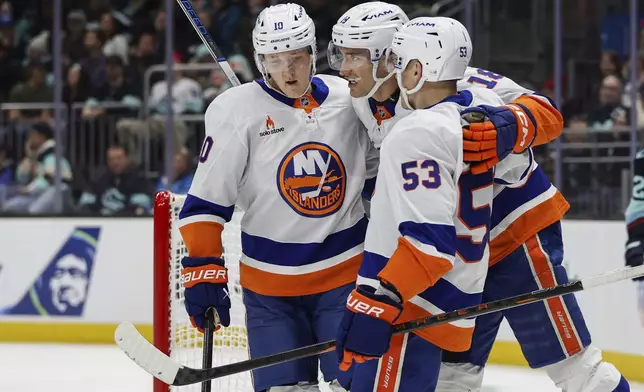 New York Islanders left wing Pierre Engvall (18) celebrates with teammates Simon Holmstrom (10) and Casey Cizikas (53) after scoring against the Seattle Kraken during the first period of an NHL hockey game, Saturday, Nov. 16, 2024, in Seattle. (AP Photo/Rio Giancarlo)