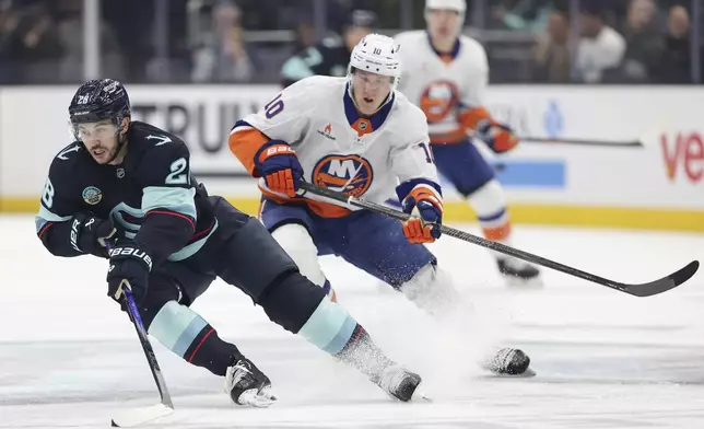 Seattle Kraken defenseman Joshua Mahura (28) skates against New York Islanders right wing Simon Holmstrom (10) during the first period of an NHL hockey game, Saturday, Nov. 16, 2024, in Seattle. (AP Photo/Rio Giancarlo)