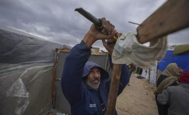 A Palestinian secures his tent as storm clouds loom over a camp for displaced Palestinians on the beach front in Deir al-Balah, Gaza Strip, Tuesday Nov. 26, 2024. (AP Photo/Abdel Kareem Hana)