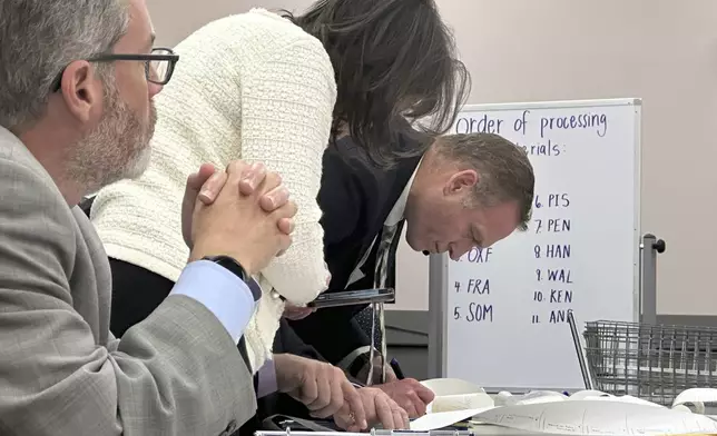 Attorneys and observers review a printout from a voting machine to ensure the numbers match with the reported results as the state conducts additional tabulations under ranked choice voting in a congressional race, Tuesday, Nov. 12, 2024, in Augusta, Maine. (AP Photo/David Sharp)