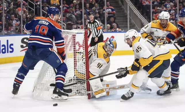 Nashville Predators' Alexandre Carrier (45) and Edmonton Oilers' Zach Hyman (18) scramble for the rebound from goalie Scott Wedgewood (41) during the second period of an NHL hockey game, Thursday, Nov. 14, 2024 in Edmonton, Alberta. (Jason Franson/The Canadian Press via AP)