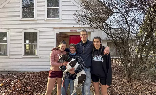 The Mackenzies, from left to right, Lila, Jenny, John, Kate and their dog Hester pose in front of their new house in Craftsbury, Vt. on Nov. 17, 2024. (AP Photo/Lisa Rathke)