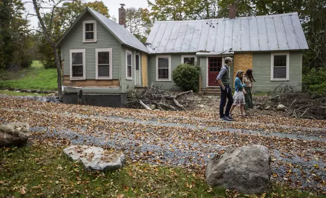 John, left, Jenny and Lila, right, Mackenzie walk around their flood-damaged property in Peachman, Vt. on Sept. 23, 2024. (AP Photo/Dmitri Beliakov)