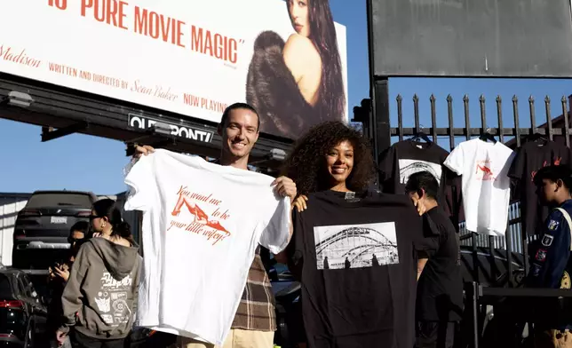 Van Tillian, left and Kapri Matlock pose for a photo with tee-shirts they got at a Pop-Up merchandise event for the movie Anora on Saturday, Nov. 9, 2024 in Los Angeles. (AP Photo/Richard Vogel)